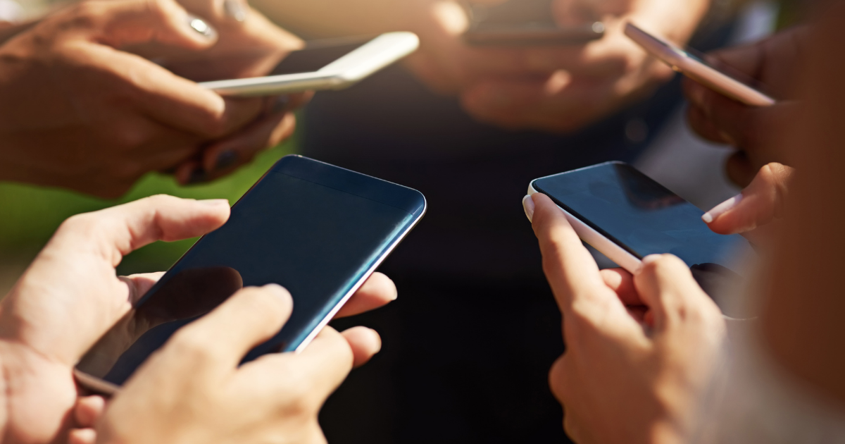 Mehrere Personen halten ihre Smartphones eng beieinander und tippen darauf, wobei nur die Hände und Geräte sichtbar sind.