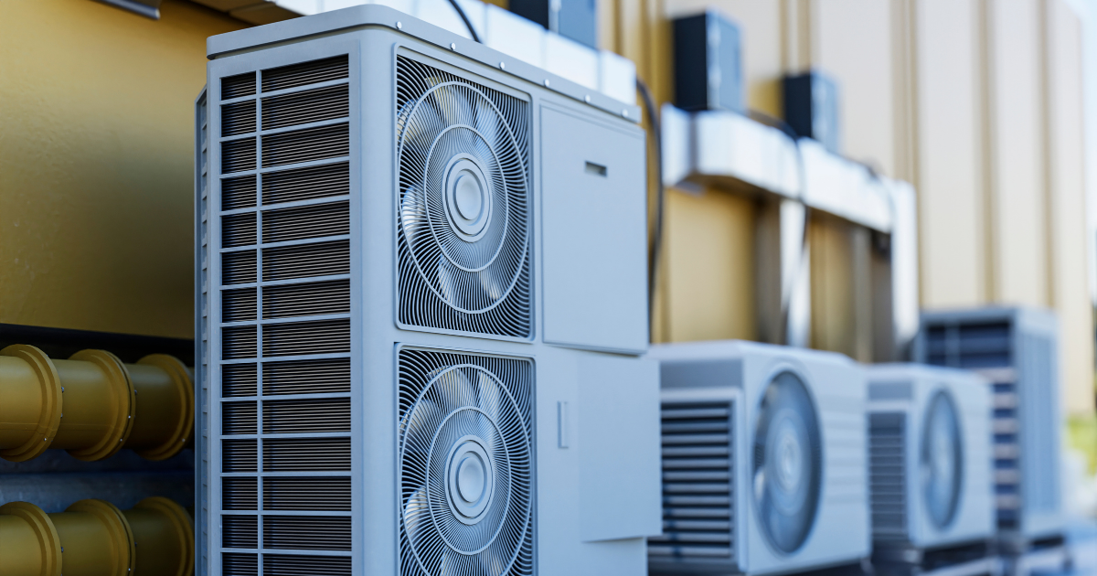 Reihe moderner Außengeräte von Wärmepumpen oder Klimaanlagen mit sichtbaren Ventilatoren und Metallgittern, installiert außerhalb eines Gebäudes.