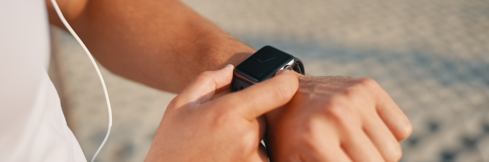 Nahaufnahme einer Person im Sportoutfit, die eine Smartwatch am Handgelenk bedient.
