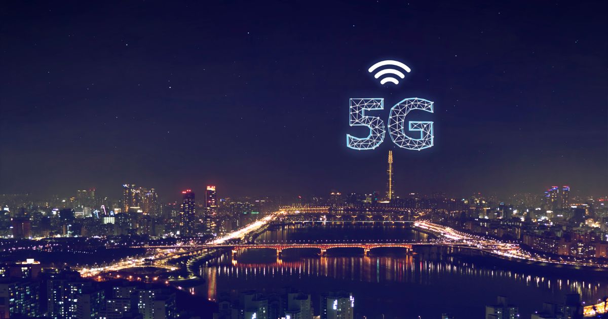 Großstadt in der Nacht, über einem Hochhaus das 5G-Symbol