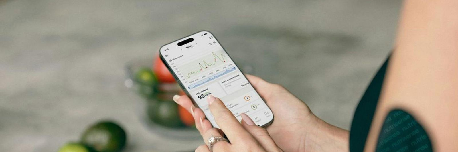 Frau mit Smartphone betrachtet App-Daten, im Hintergrund Gemüse