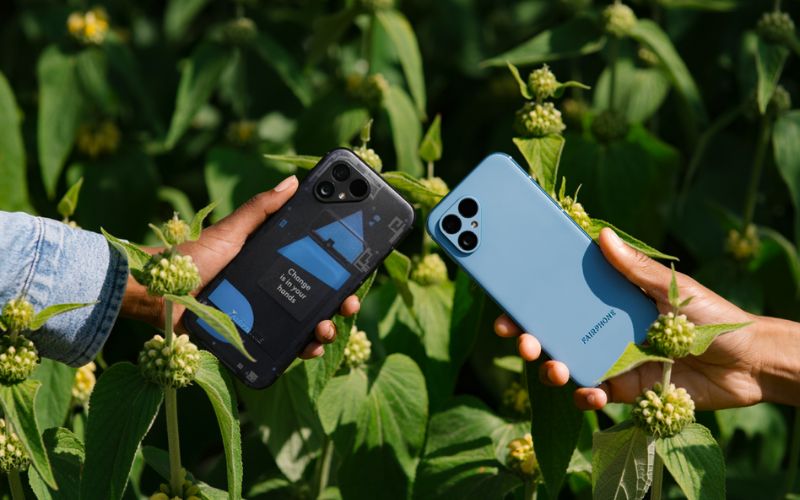 Zwei Smartphones weden nebeneinander gehalten, dahinter eine Wiese