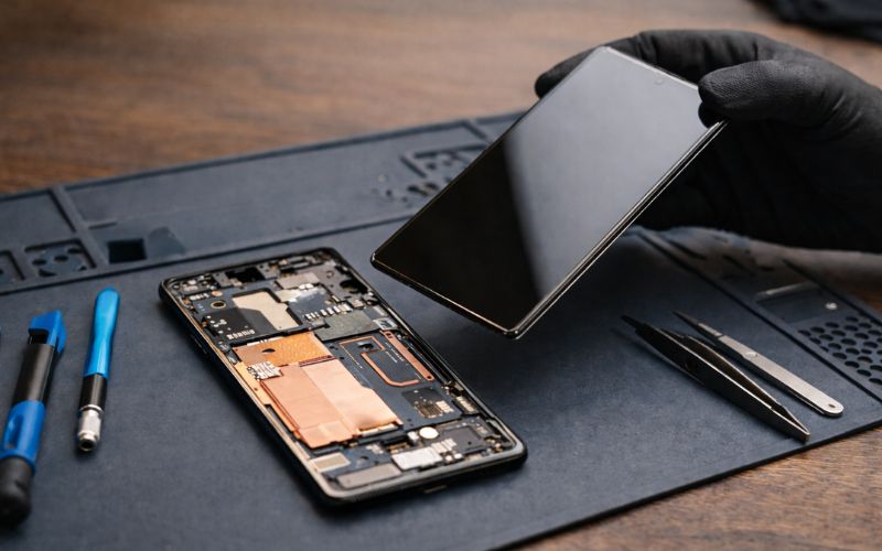 Smartphone liegt auf einem Tisch neben Werkzeug, das Display wurde entfernt
