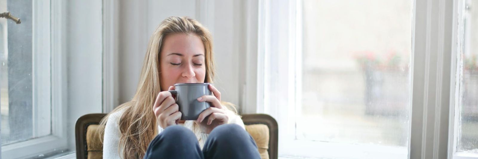 Frau sitzt entspannt auf einem Stuhl und trinkt Kaffee