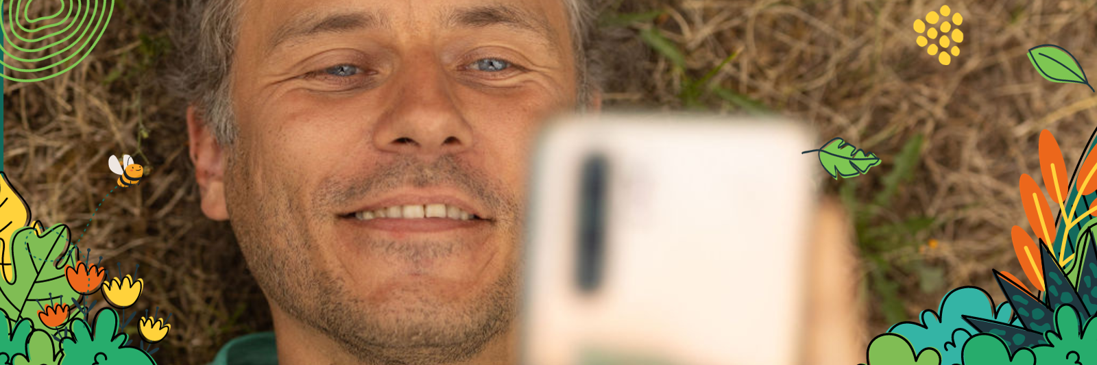 Ein Mann schaut lächelnd auf sein Smartphone