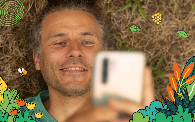 Ein Mann schaut lächelnd auf sein Smartphone