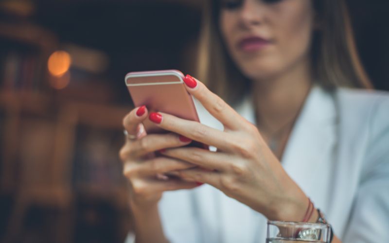 Frau hält rosa Smartphone in der Hand