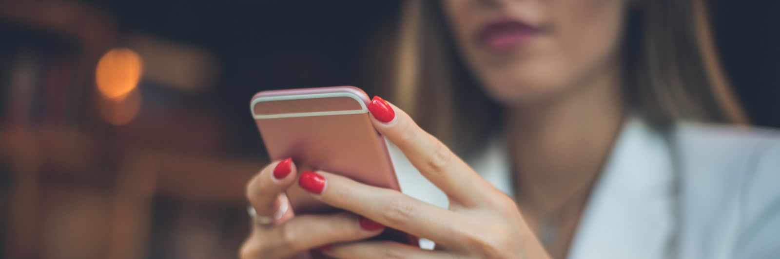 Frau hält rosa Smartphone in der Hand