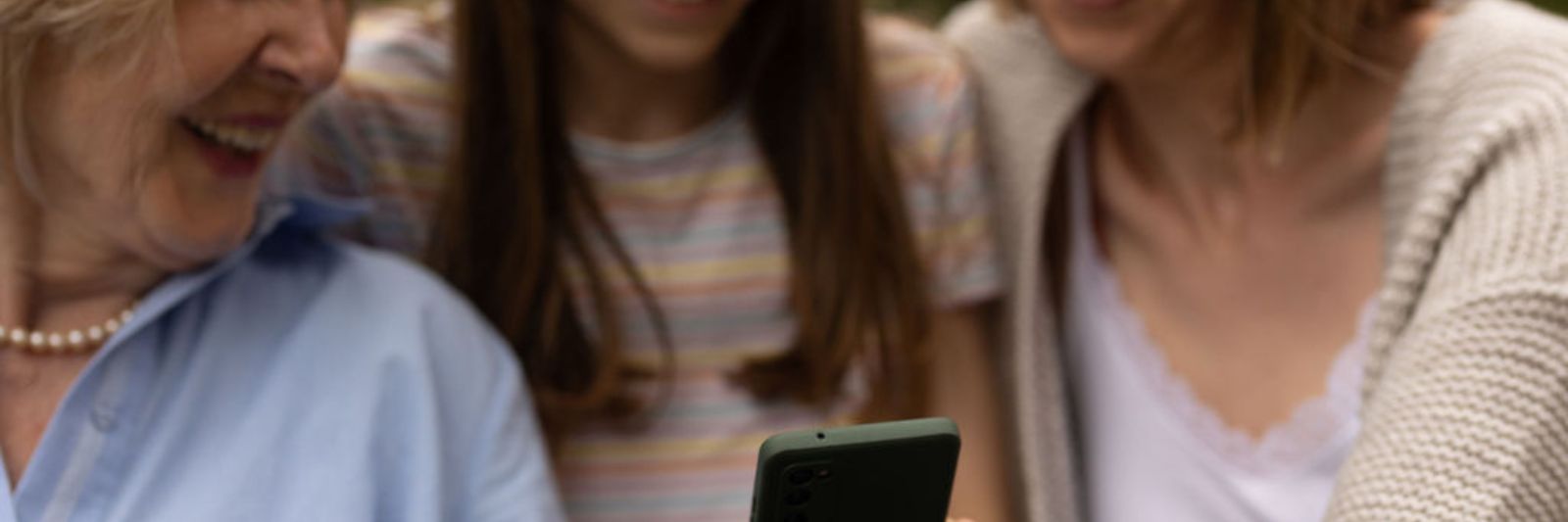 3 Personen schauen gemeinsam auf ein Smartphone