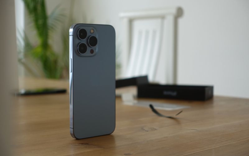 iPhone steht auf Tisch, dahinter Stuhl und Pflanze