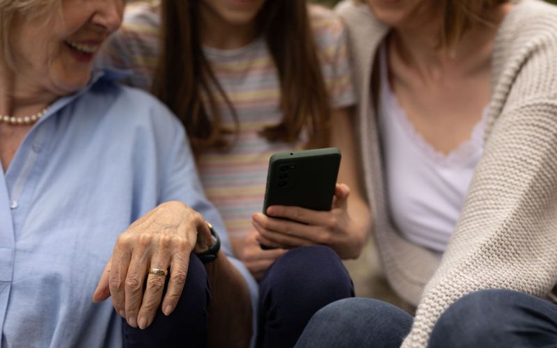 Drei Menschen schauen gemeinsam auf ein Smartphone