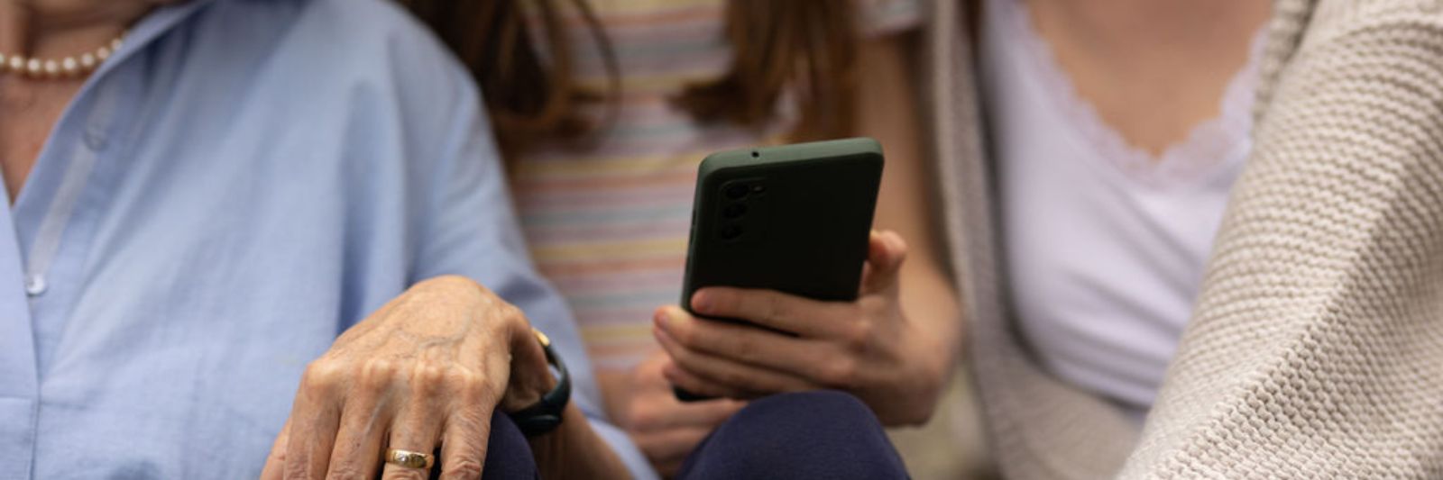 Drei Menschen schauen gemeinsam auf ein Smartphone