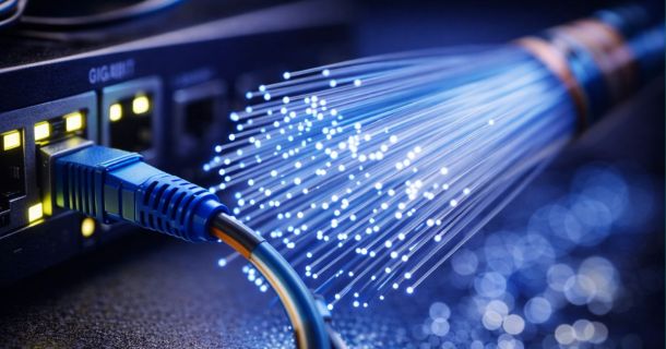 LAN-Kabel steckt in Box, rechts daneben ein offenes, leuchtendes Glasfaser-Kabel